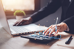 Man at desk on calculator and laptop