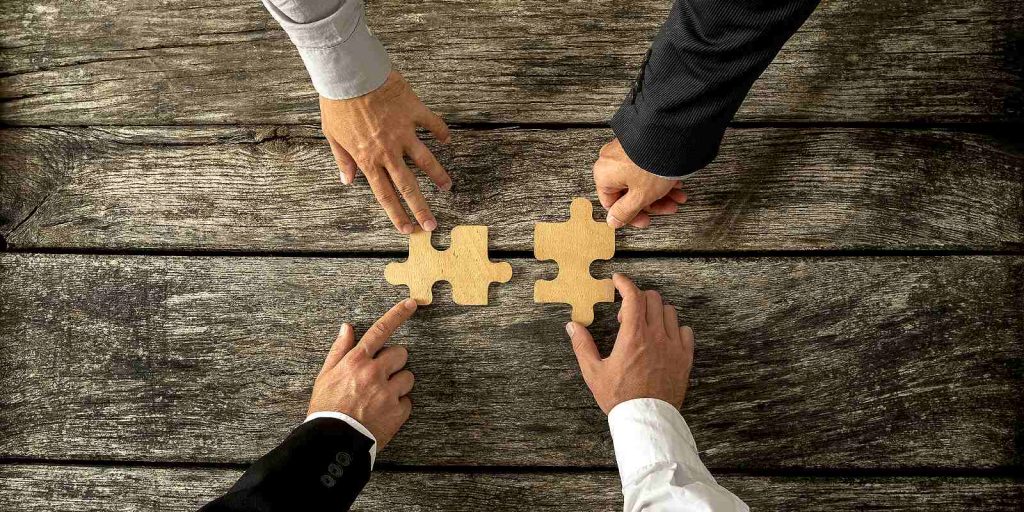 Group of business men joining two puzzle pieces. M&A integration planning concept