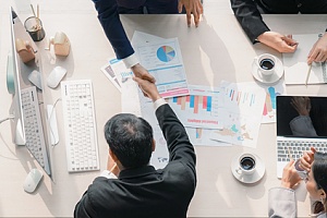 two business men shaking hands at a meeting table